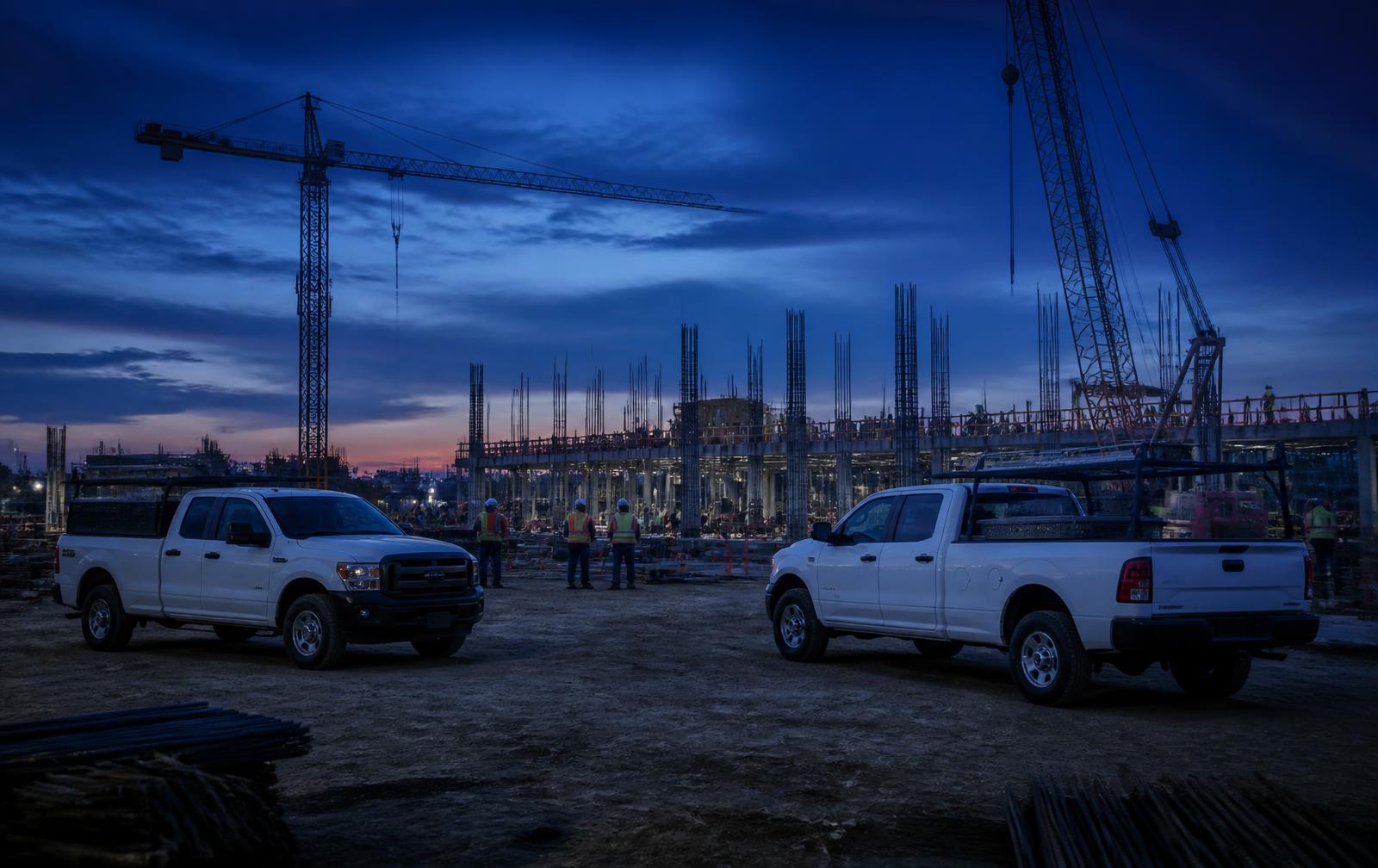 Pickups de trabajo en una obra en construcción al anochecer